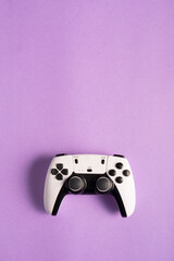 A white and black gaming controller is a purple background. The buttons, joysticks, and modern...
