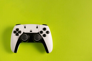 A white and black gaming controller on a green background. The buttons, joysticks, and modern design stand out, creating a striking contrast that highlights the device's sleek look.