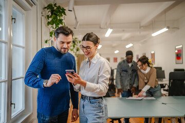 Fototapeta premium male and female colleagues use mobile phone at office
