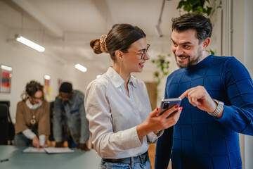 male and female colleagues use mobile phone at office