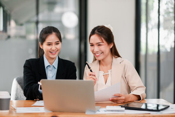 Two businesswomen discussing a project in a contemporary office, showcasing teamwork and collaboration.