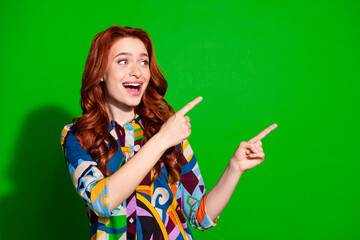 Young woman pointing with enthusiasm against a vibrant green backdrop in a colorful printed shirt