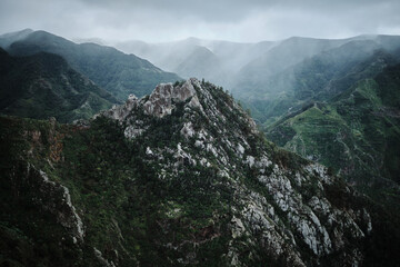 Dramatic misty mountain range landscape.  Rugged peaks and lush green valleys shrouded in fog create a breathtaking scene. Perfect for travel, nature, or adventure themes.