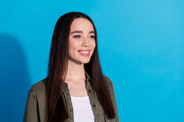 Fototapeta premium Portrait of a smiling young woman with long hair and casual attire against a vibrant blue background