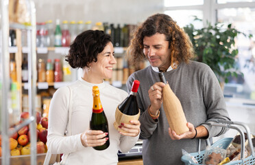 Husband and wife shopping together at the supermarket - choosing bottles of wine
