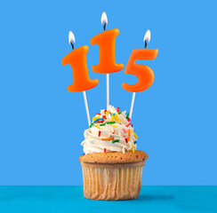Orange candle number 115 - Birthday cupcake on blue background
