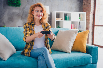 Photo of nice young blonde girl sit couch play video game wear yellow plaid clothes enjoy modern...
