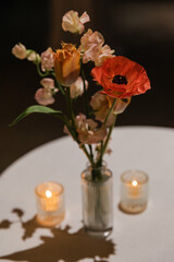 Vibrant floral arrangement on a table with candles creating a cozy ambiance in a dimly lit setting