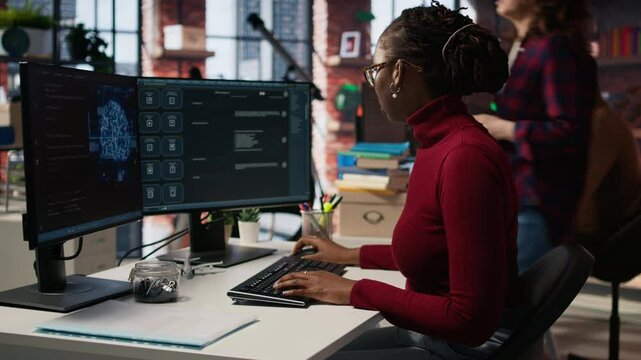 IT startup worker using large language model application to get help with coding tasks. Woman interacting with AI LLM chatbot PC GPT software on PC in software development workplace, camera A