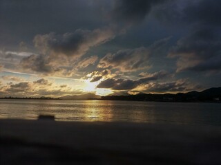 sunset on a river with mountains in the background and scattered clouds