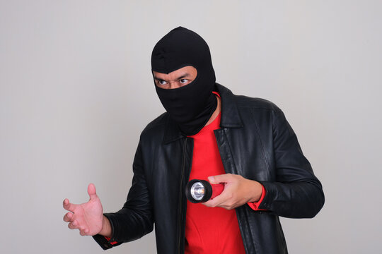 A bad guy wearing balaclava use a flashlight when lurking
