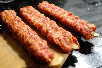 Adana Kebab, the traditional taste of Turkish cuisine. A housewife cooks homemade Adana kebab in a pan. Close-up footage of cooking lavash, kebab in a pan. Traditional Turkish cuisine.