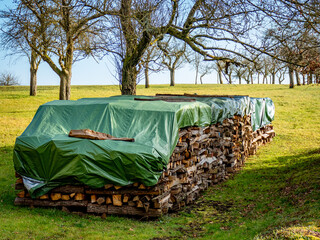 Abgedecktes und gestapeltes Brennholz im Freien