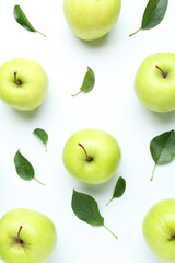 Green apples and leaves on white background, flat lay