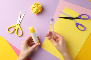 Woman with glue, scissors and colorful paper at table, top view