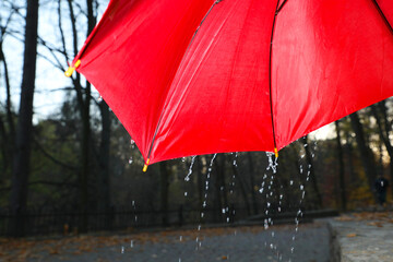 Open red umbrella under pouring rain outdoors, closeup