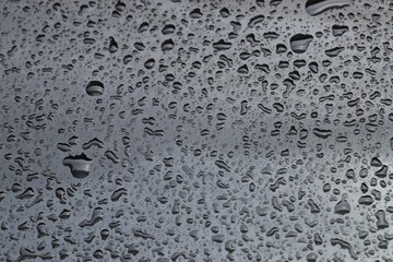 Water drops on grey glass surface, closeup