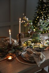 Christmas place setting with festive decor on wooden table in room
