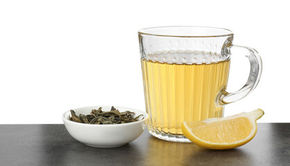 Refreshing green tea in cup, slice of lemon and dry leaves on grey textured table against white background. Space for text