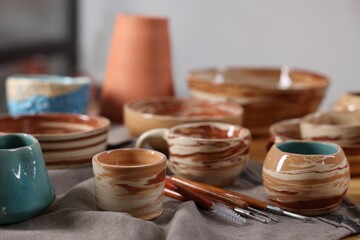 Different beautiful pottery and set of clay crafting tools on table indoors, closeup