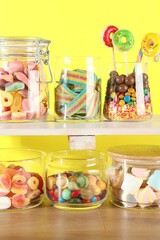 Candy bar. Many different sweets on wooden table against yellow background