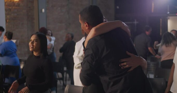 Diverse congregation members exchanging hugs and smiles in a modern church setting, creating a sense of community, connection, and shared spirituality