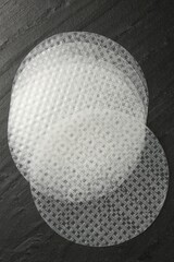 Edible rice paper sheets on dark textured table, flat lay