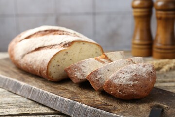 Cutting board with fresh bread on wooden table, closeup