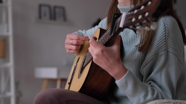 A person playing guitar in a comfortable living room, showcasing various strumming patterns, lower viewing angle. The warm atmosphere invites relaxation while enjoying the music.