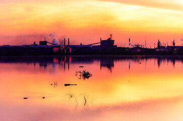 Silhouette of industrial waterfront district with  orange sky