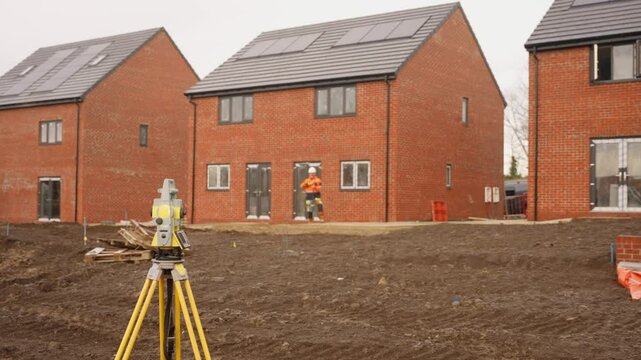 Construction workers on site at new residential development in early morning light overseeing house building progress