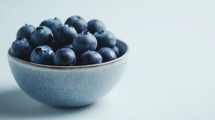 Fresh ripe blueberries, dark blue ceramic bowl, close-up view, organic healthy fruit, rustic textured background