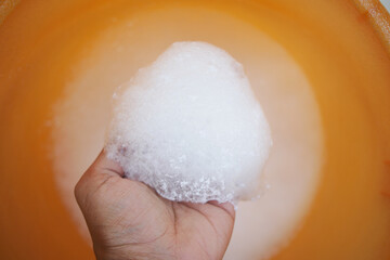 Close-Up of a Hand Holding a Foam Ball Over an Orange Background