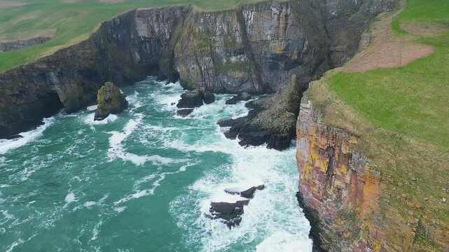 Drone footage of the North Sea waves crashing on the cliffs on the coast of Whaligoe town, Scotland