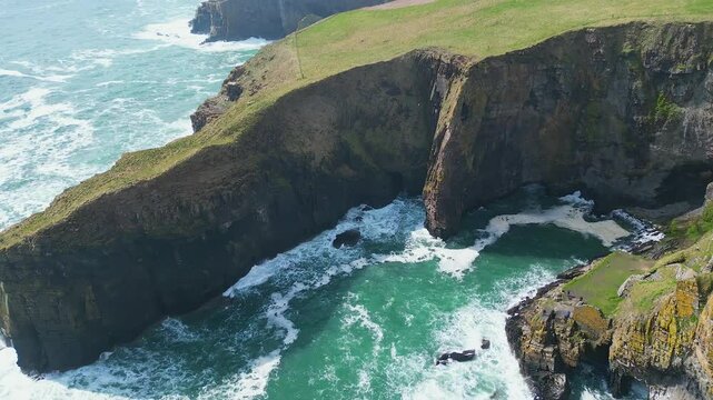 Aerial footage of the Elephant Cliff and Whaligoe Steps on a sunny day in Whaligoe town, Scotland