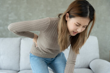 Asia beautiful woman holding her lower back while and suffer from unbearable pain health and...