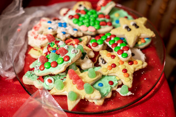 Plate of colorful, hand-decorated Christmas cookies featuring festive shapes like stars and trees, topped with icing and candy 