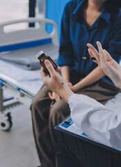 doctor consulting senior old patient filling form at consultation. Professional physician wearing white coat talking to mature woman signing medical paper at appointment visit in clinic.