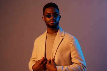 Stylish young man in trendy outfit with sunglasses, showcasing confidence against a colorful gradient background in a fashion forward style