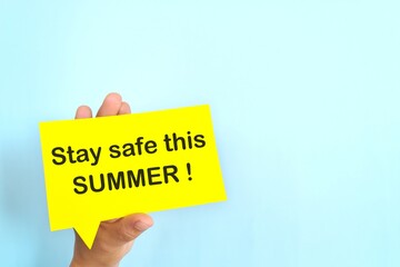 Summer essentials and safety tips reminder concept. Hand holding bright yellow speech bubble in blue background.