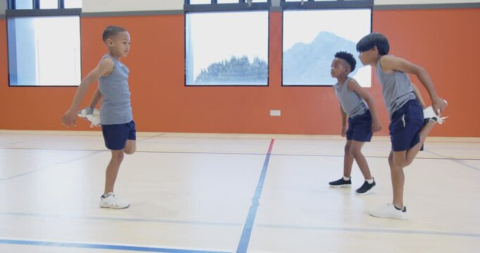 In school gym, three boys jumping rope and exercising together
