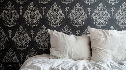 White pillows on a bed with a dark, ornate damask wallpaper headboard.