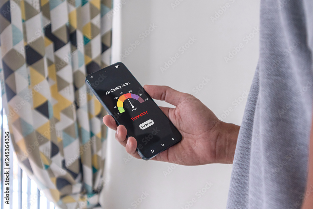 Wall mural man checking air quality index using an app on his smartphone