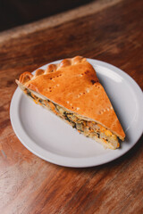 Meat pie with egg on a small plate on a wooden table.