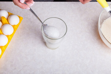 Making cupcakes at home. A woman prepares Easter cakes in the kitchen by whipping soda in a glass.