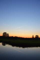 Beautiful view of sunset sky above reflected on calm river below