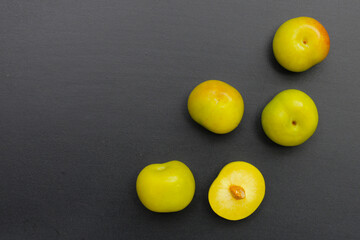 Fresh green plum fruit on dark background.