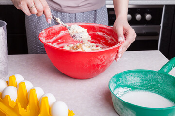 Making cupcakes at home. A woman prepares Easter cakes in the kitchen, mixing the dough with raisins