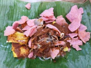 delicious serving of Ketupat Tahu Bandung, featuring rice cakes, tofu, bean sprouts, and a rich peanut sauce, all topped with crispy pink crackers.
