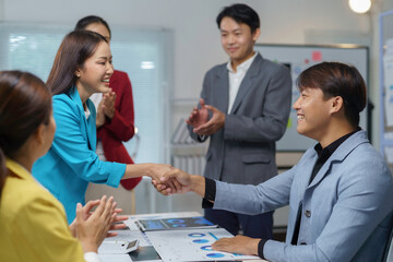 Asian businesspeople shaking hands celebrating successful deal in office meeting